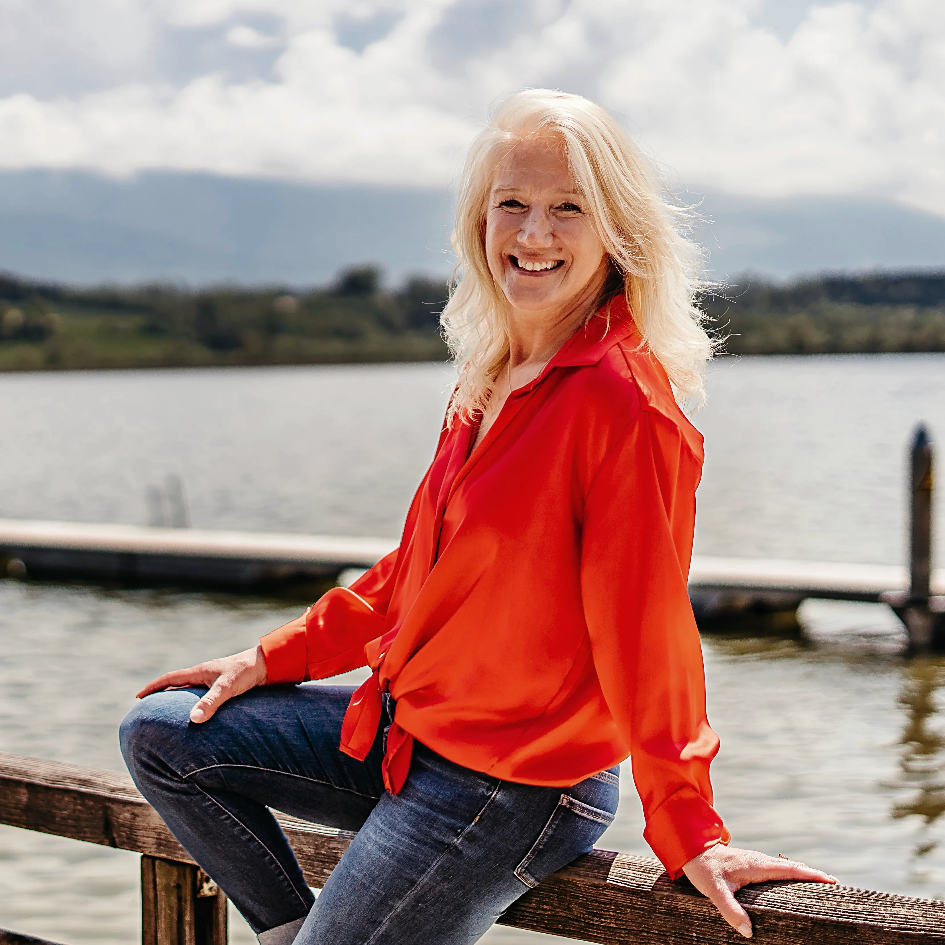 Sabine Kohl mit roter Bluse auf Geländer am See